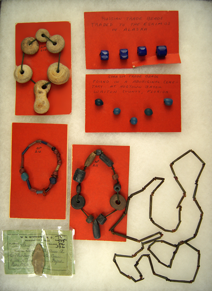 Frame of miscellaneous cards of beads, including an Egyptian mummy bead necklace.