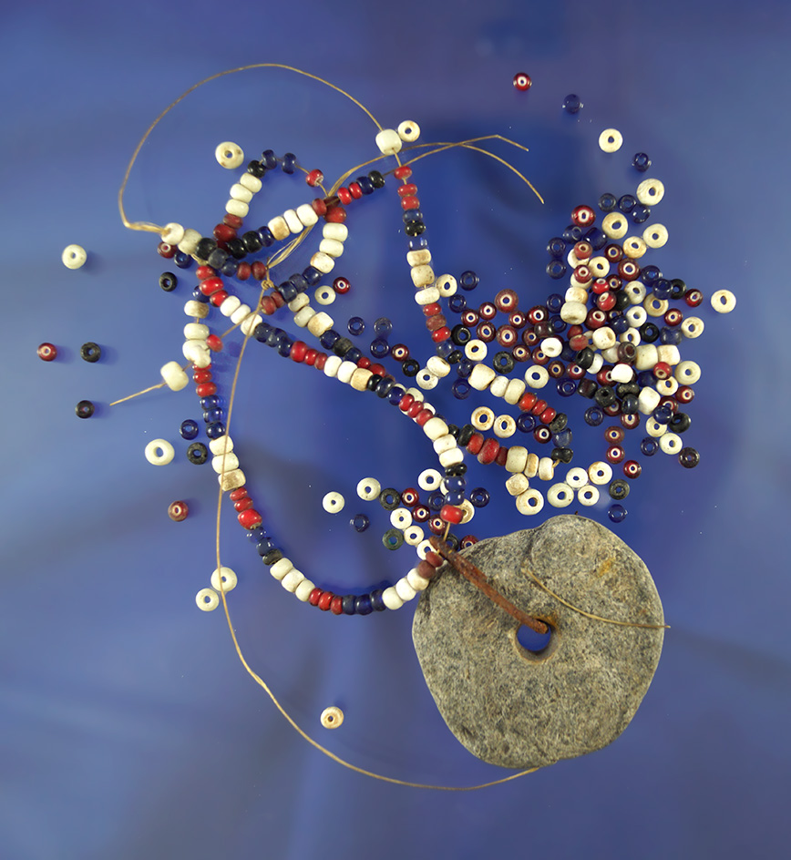 Group of strung beads and a drilled stone Pendant found at a site in California.