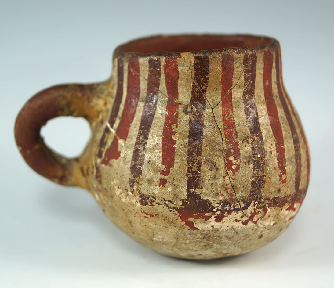 Miniature 2 1/4" tall southwestern Tesuque pitcher that is reddish and cream in color.