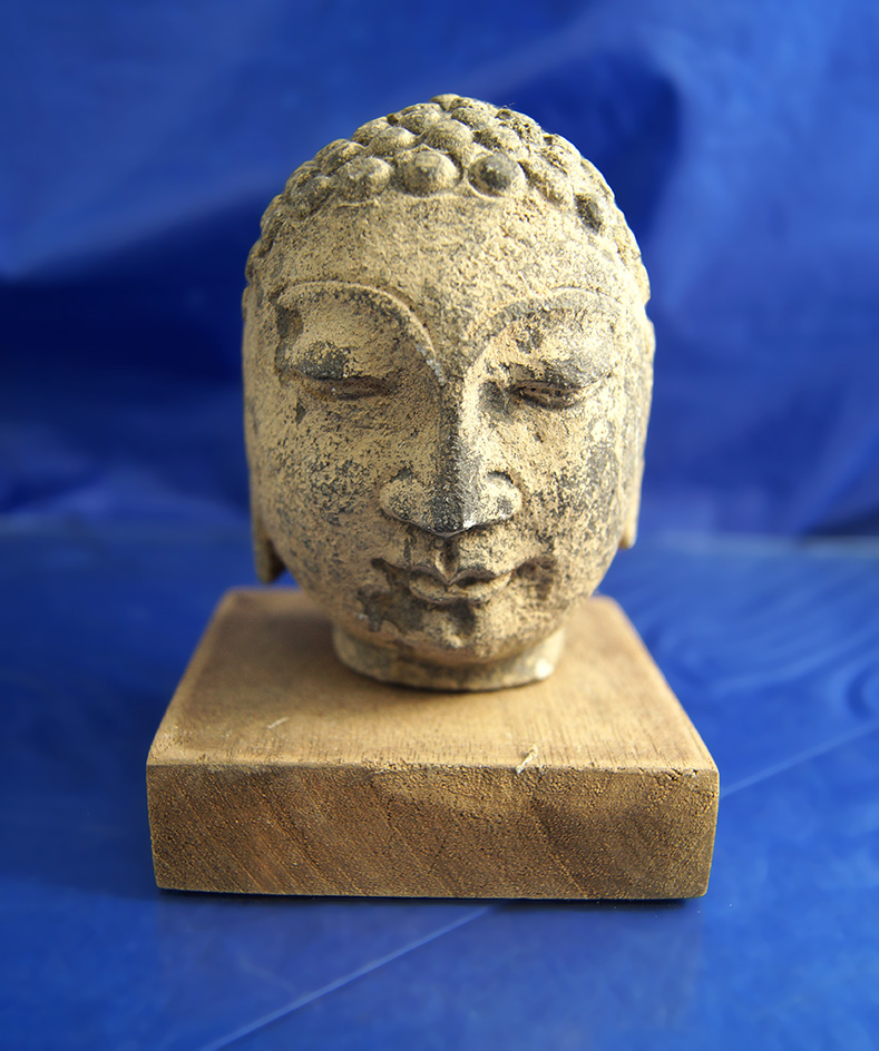 3 1/2" carved stone Buddha head on a wooden stand from the Orient.