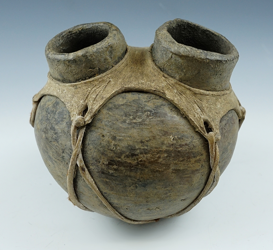 5 1/2" wide x 4 3/4" tall double spout pottery vessel with original leather wrap. Pre-Columbian.